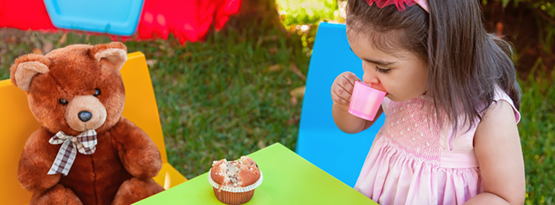 Niña compartiendo merienda con un peluche