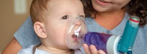 Bebé con asma utilizando un aparato para respirar mejor