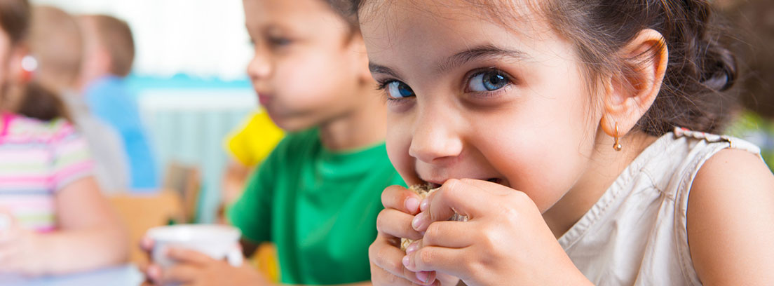 Grupo de niños en el cole desayunando