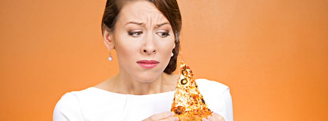 Mujer sujetando una pizza y con cara de no saber si comérsela.