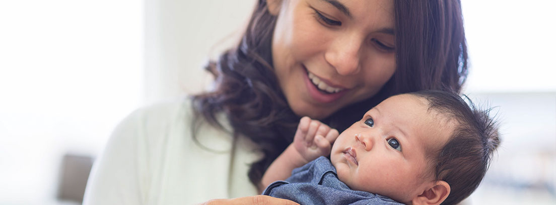 Bebé en primer plano con su madre sonriente detrás