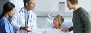 Un médico y una enfermera hablan con una mujer hospitalizada y su pareja