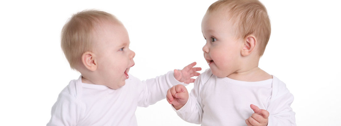 Dos niños bebé con un body blanco relacionándose