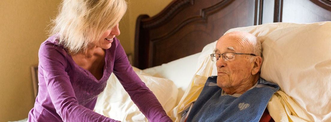 Mujer atendiendo a un anciano que está acostado