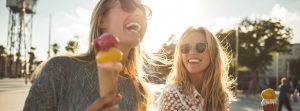 Dos chicas jóvenes sonríen mientras sujetan un helado