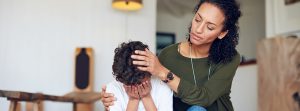 Niño tapándose la cara y madre consolándole.