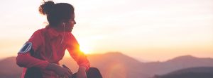 Deportista con auriculares haciendo una pausa durante la puesta de sol