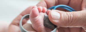 El pié de un bebe y las manos de un adulto realizándole una prueba