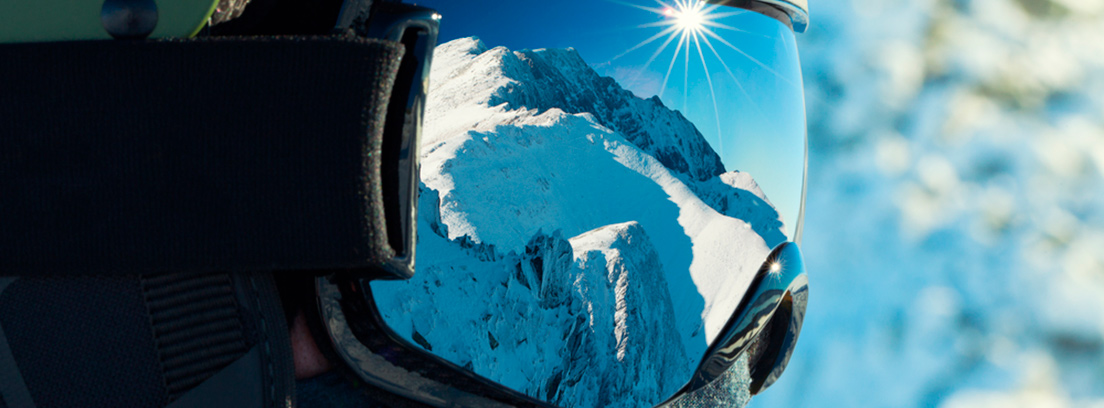 Paisaje nevado reflejado en las gafas de un casco de esquí