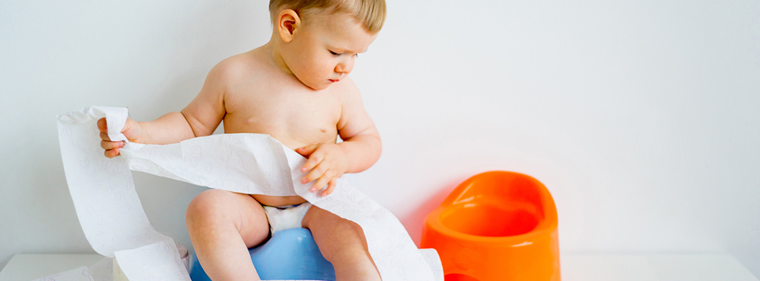 Niño sentado en un orinal mirando a otro mientras sujeta papel higiénico