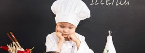 Niño vestido de chef apoyado en una mesa