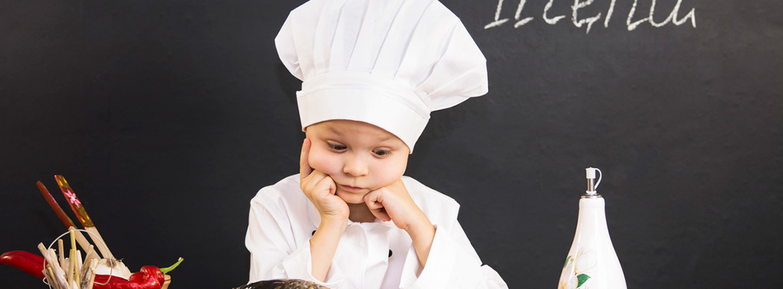Niño vestido de chef apoyado en una mesa