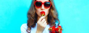 chica con gafas de sol rojas comiendo fresas