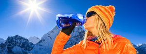 Una mujer con equipación deportiva bebe agua en la montaña