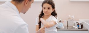 Una niña señala un dolor en el codo en la consulta de un traumatólogo