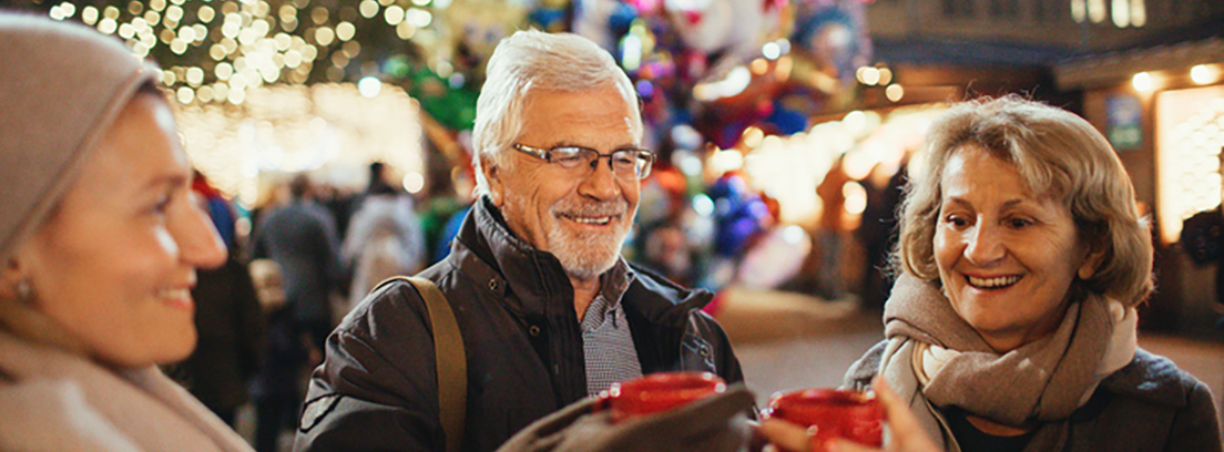 Una pareja de adultos mayores sonríen en un ambiente navideño