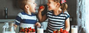 Pareja de niños comiendo fresas con leche