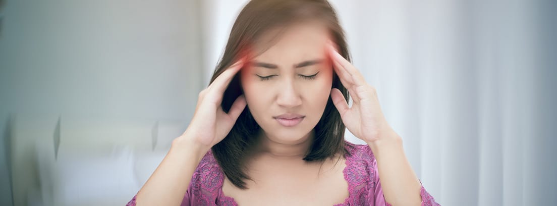 Neuritis vestibular: mujer con las manos sobre las sienes con sensación de vértigo