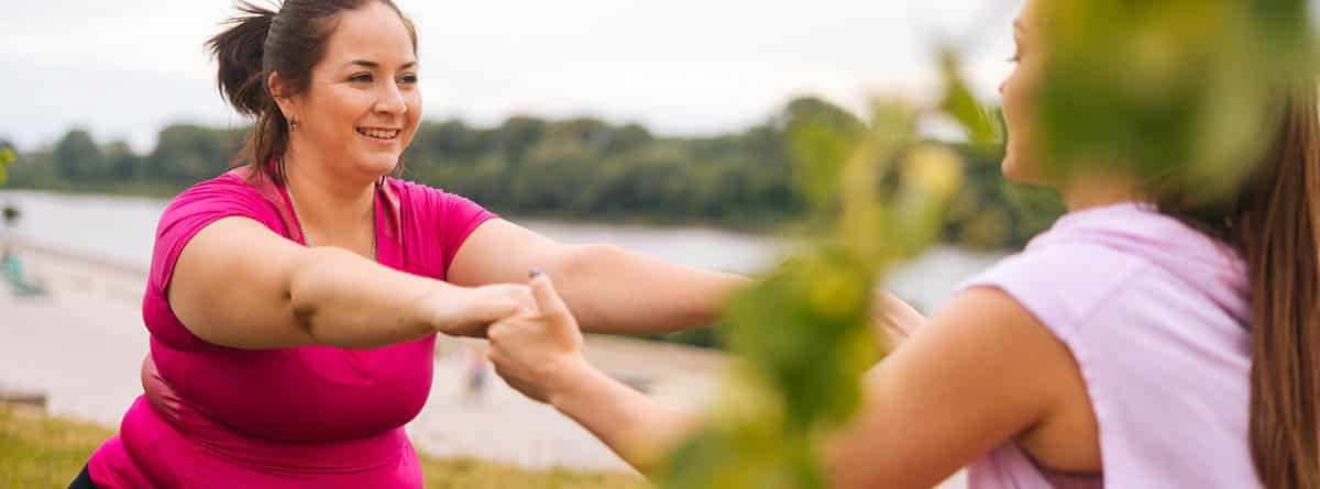 obesidad y sobrepeso: mujer obesa haciendo ejercicio ayudada por un especialista