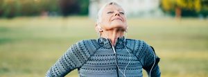 Mujer adulta respirando profundamente vestida de deporte y con auriculares puestos