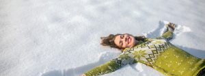 Mujer con sonrisa de relajación tumbada en la nieve