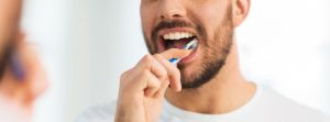 Joven con barba se cepilla los dientes frente al espejo