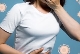 Persona con una mano en la barriga y otra en la boca y dibujos de virus en el fondo