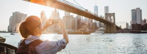 Chica haciendo una foto a un paisaje de edificios y un puente