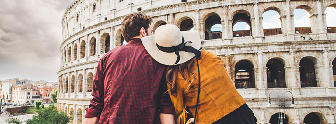 Una pareja de espaldas mirando al Coliseo de Roma