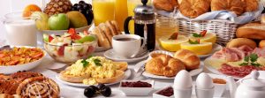 Mesa con muchas opciones de desayuno: café, zumos, bollos, pan, huevos y más