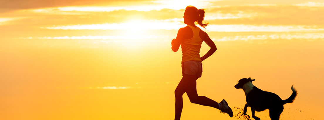 Mujer corriendo junto a un perro en la puesta de sol