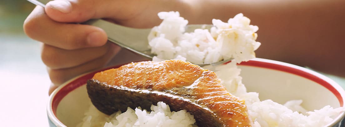 Niño comiendo salmón con arroz