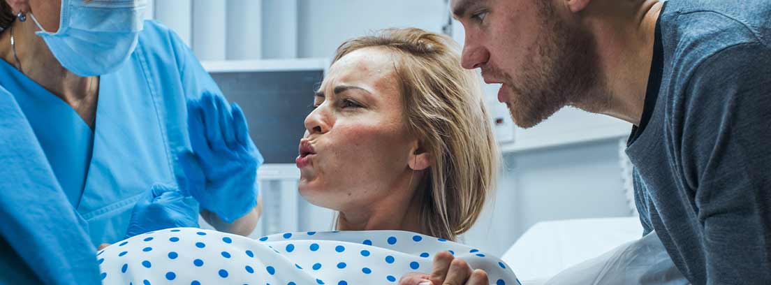 mujer en hospital de parto con el padre al lado