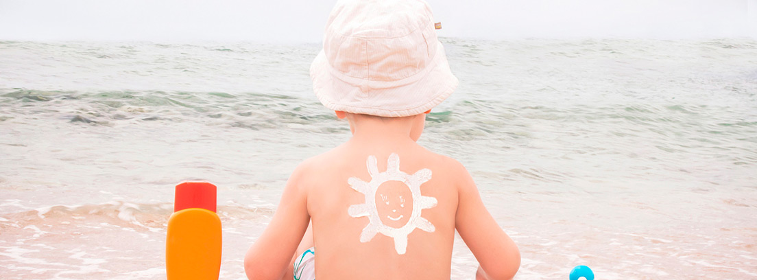 niños de espaldas al mar con un sol de crema dibujado en la piel