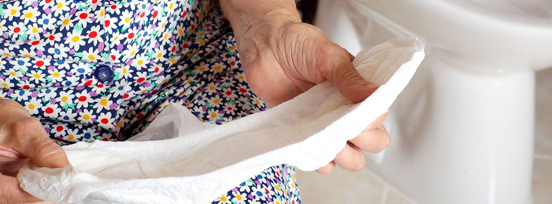 Mujer mayor con un pañal en las manos para la incontinencia urinaria