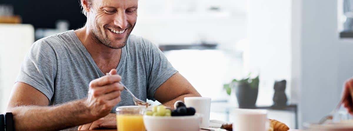 Nutrición en el hombre: hombre comiendo fruta y un vaso de zumo de naranja