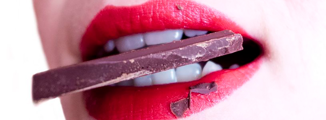 Primer plano de una boca de mujer mordiendo chocolate