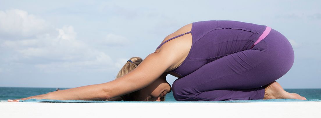 mujer en la playa practicando yoga