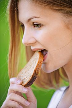 mujer comiendo una rebanada de pan
