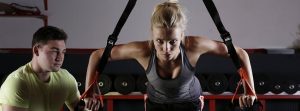 Mujer entrenando con su preparador físico al lado