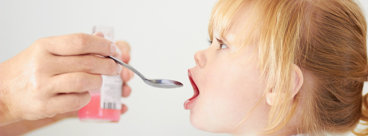 Trucos para dar medicamentos a los niños: niña tomando una cucharada de jarabe