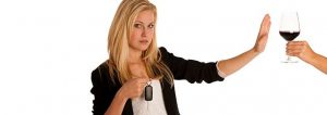 mujer rechazando una copa de vino con las llaves del coche en la mano
