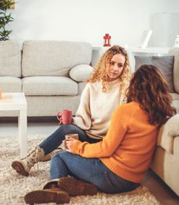 dos mujeres hablando en en suelo con una taza