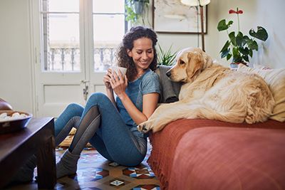 mujer sentada en el suelo y su perro en el sofá