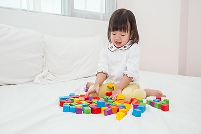 niñas sentada en la cama jugando con piezas de colores