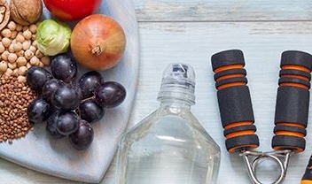 bandeja en forma de corazón con uvas, cerales, legumbres, botella y aparatos para realizar ejercicio