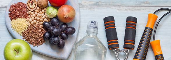 bandeja en forma de corazón con uvas, cerales, legumbres, botella y aparatos para realizar ejercicio