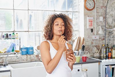 mujer comiendo un batido de chocolate en la cocina