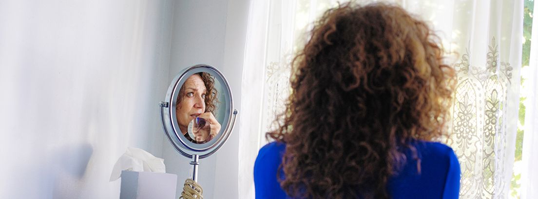 mujer mirándose al espejo con cara de peocupación