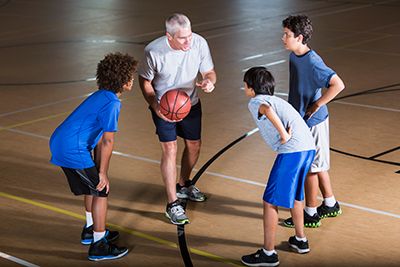niños con entrenador praticando baloncesto